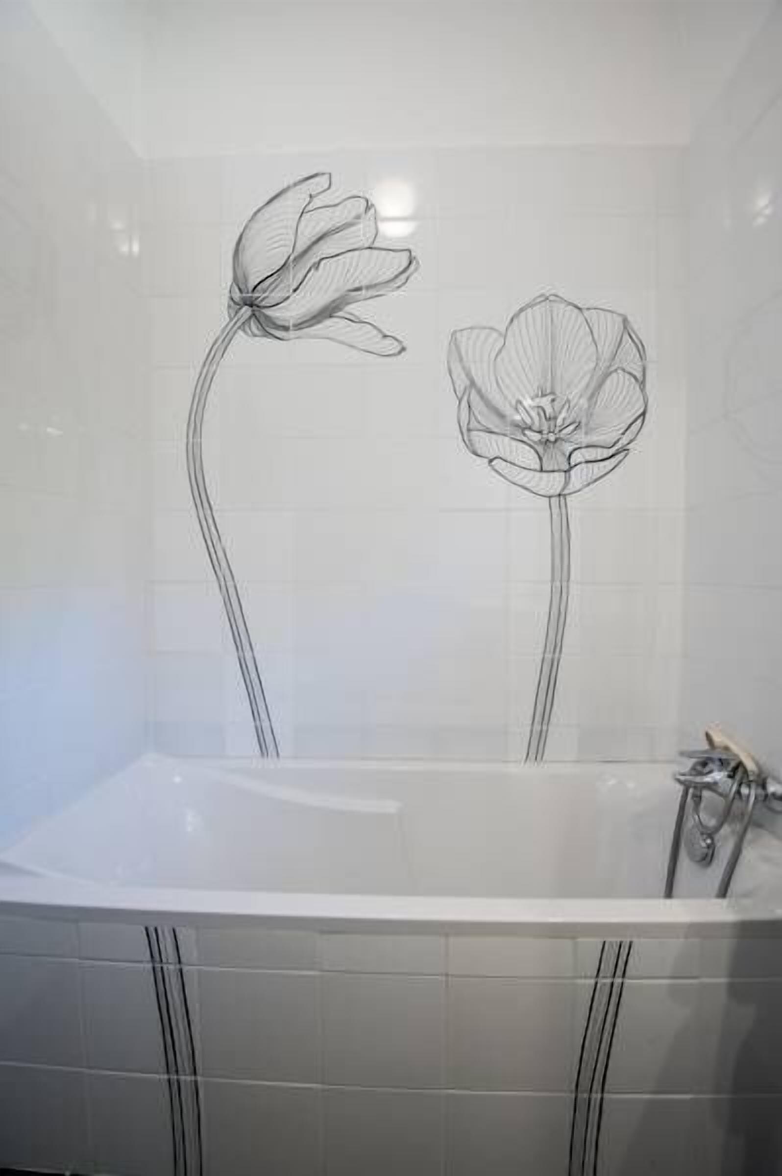 A bathroom with a white bathtub and a wall with a floral design.