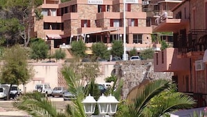A hotel with multiple floors, balconies, and a mountainous backdrop. - Hotel Kalliste (Ota)