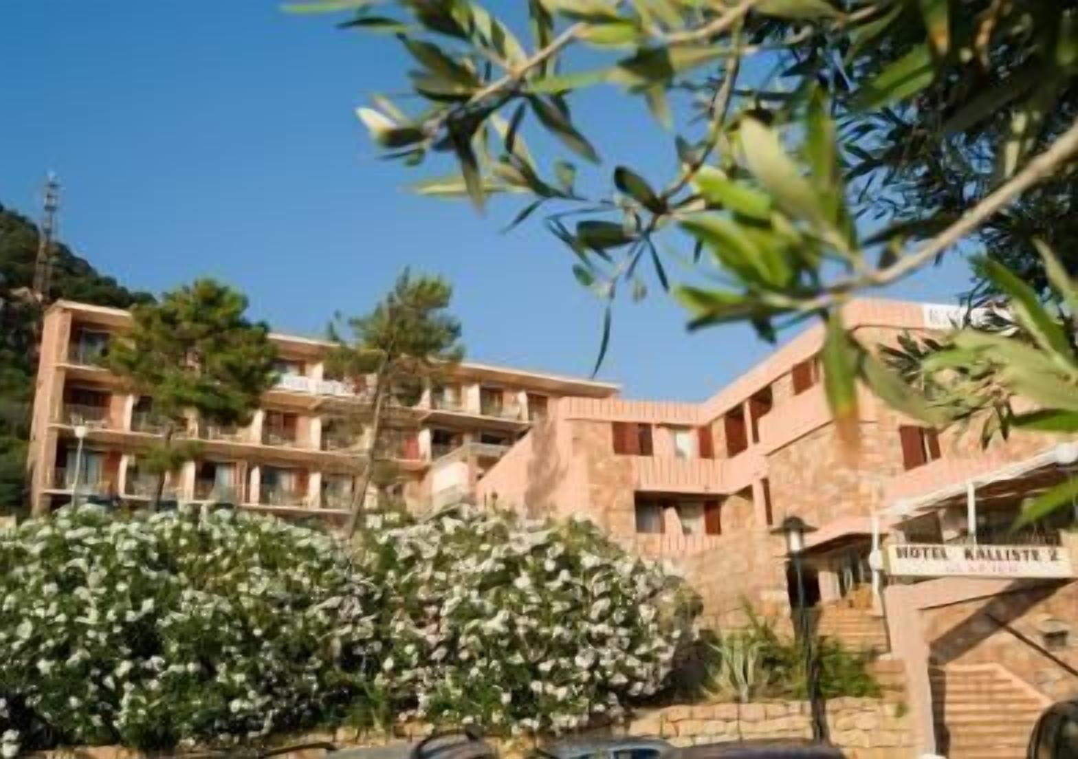 Un hotel de varios pisos con balcones, fachada de piedra y un letrero que indica que es el Hotel Kalliste 2.