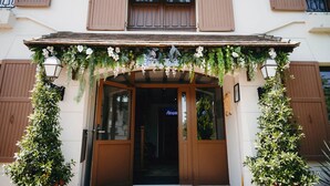 A hotel entrance with a wooden facade, a welcoming archway adorned with hanging plants, and a sign that reads "Reception." -  Hôtel & Spa Armes de Champagne (L'Epine)