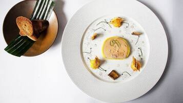 Un plato blanco con un elemento amarillo en el centro, rodeado de trozos pequeños y hojas verdes.