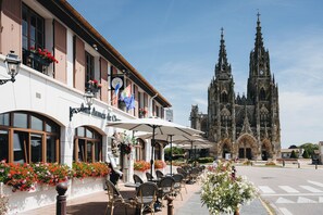 Un restaurante con terraza y una catedral al fondo.