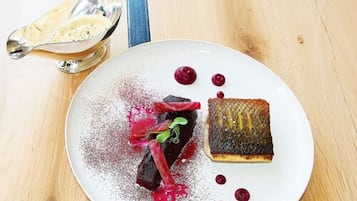 A dessert plate with a cake, berries, and a dusting of powder on a wooden table.