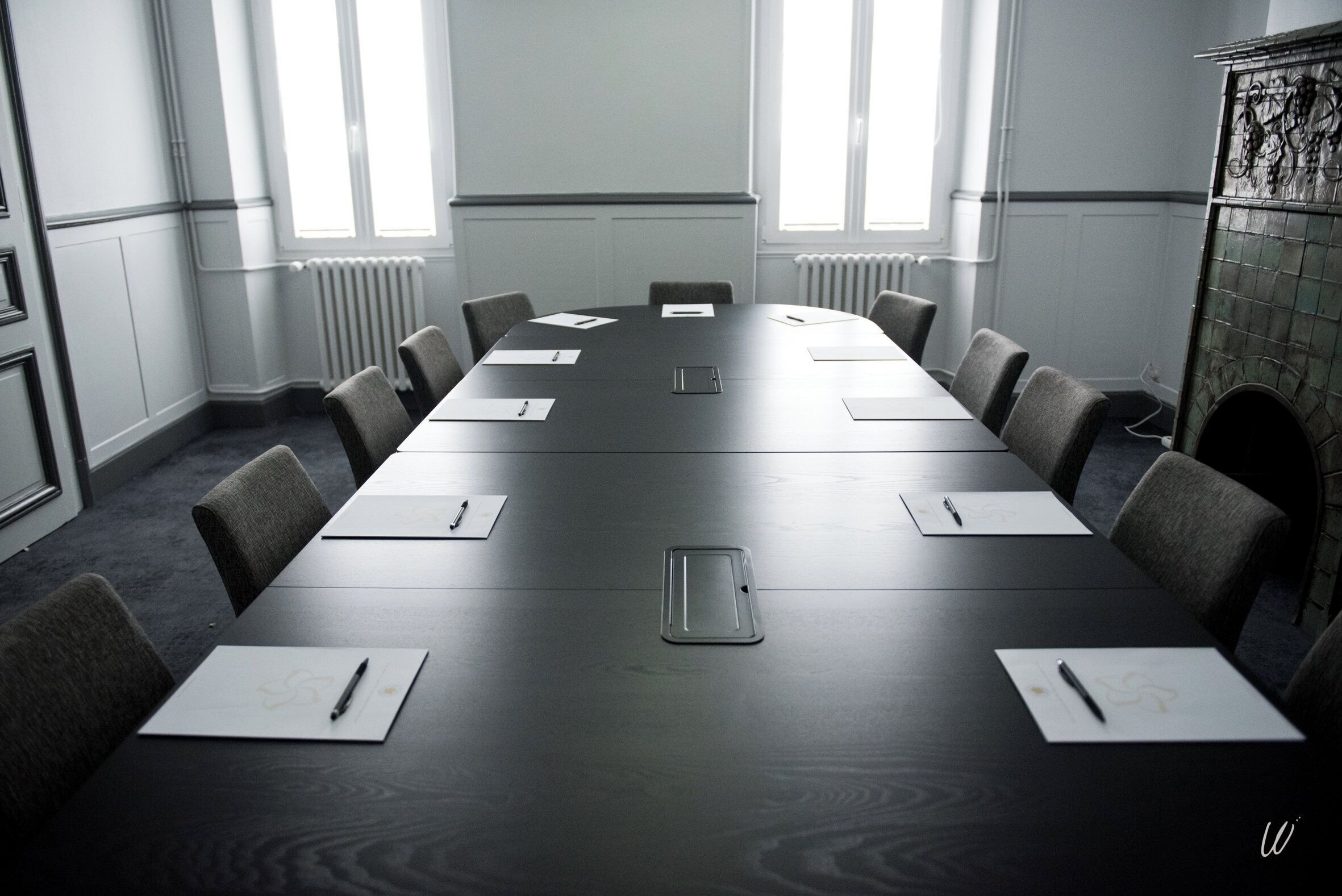 A conference room with a long table, chairs, and papers.