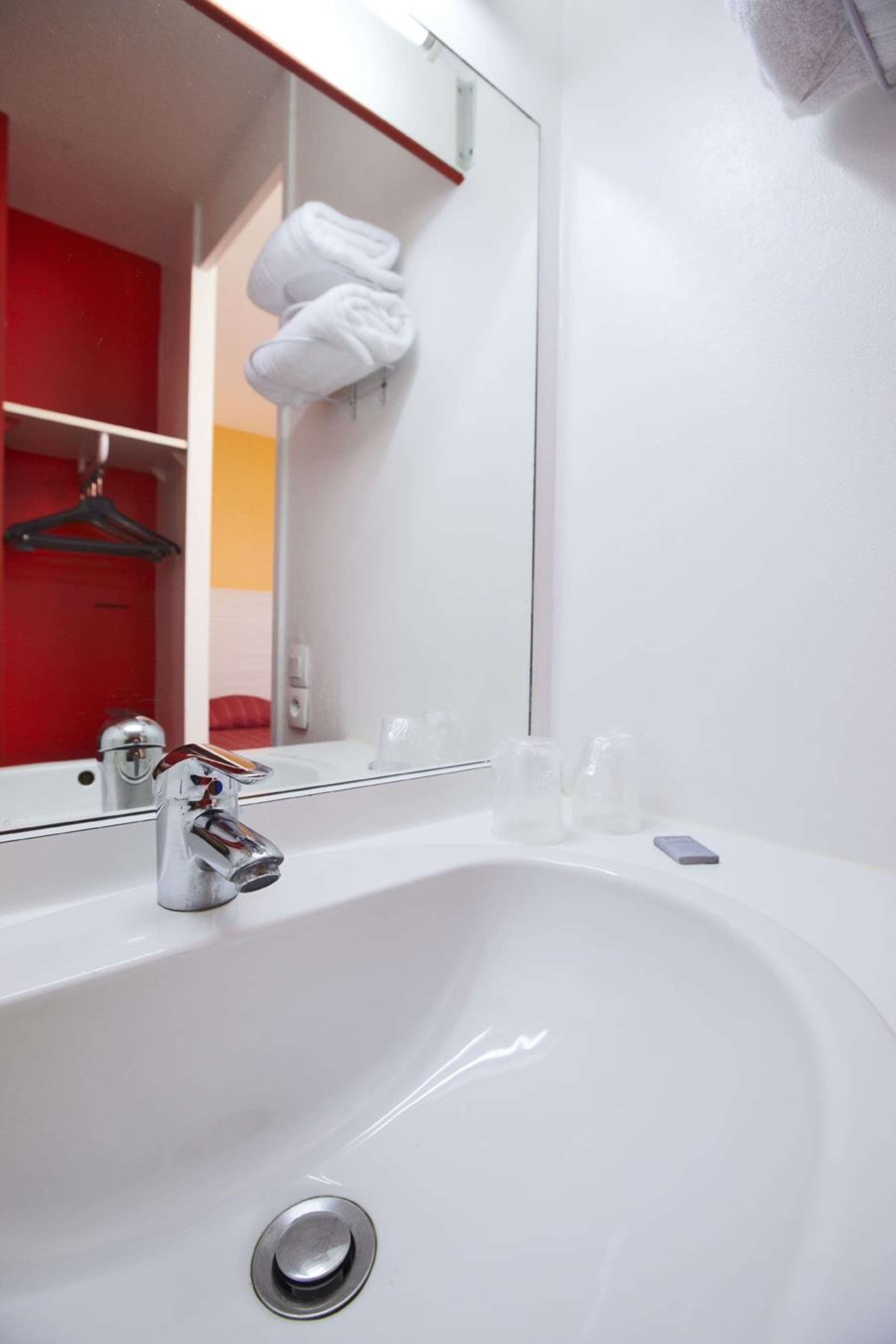 A modern bathroom with a white sink, chrome faucet, and a large mirror.