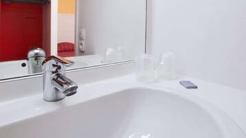 A modern bathroom with a white sink, chrome faucet, and a large mirror.