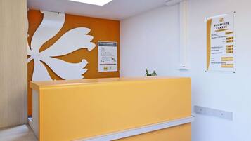 Un comptoir d’accueil avec un plan de travail jaune et un panneau mural décoratif blanc.