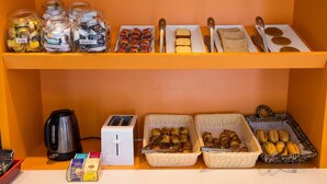 A breakfast buffet with various food items, a kettle, toaster, and baskets of pastries. - Hotel Premiere Classe Cherbourg - Tourlaville (Cherbourg-en-Cotentin)