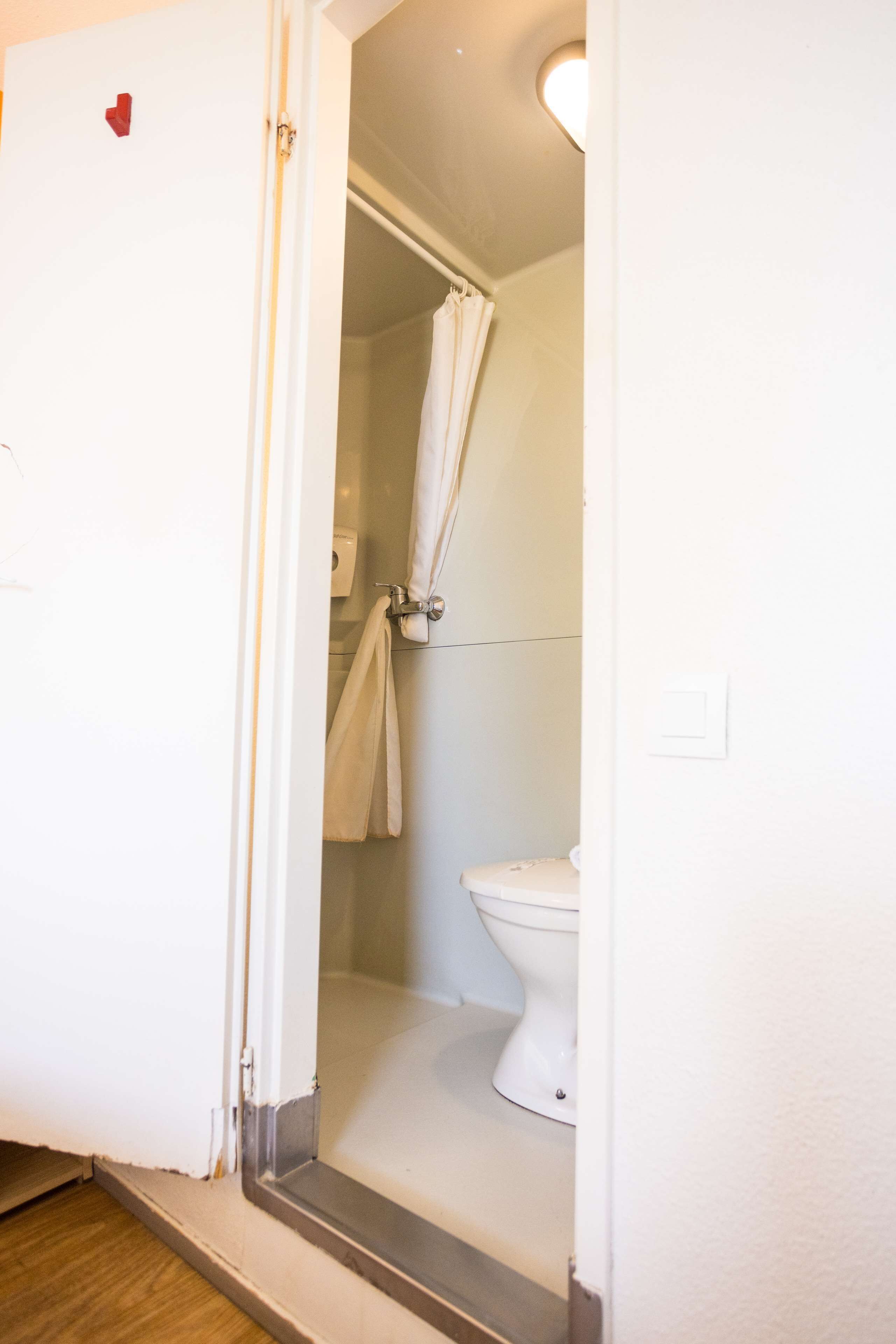 Une salle de bain avec des toilettes, un rideau de douche et une serviette accrochée au mur.