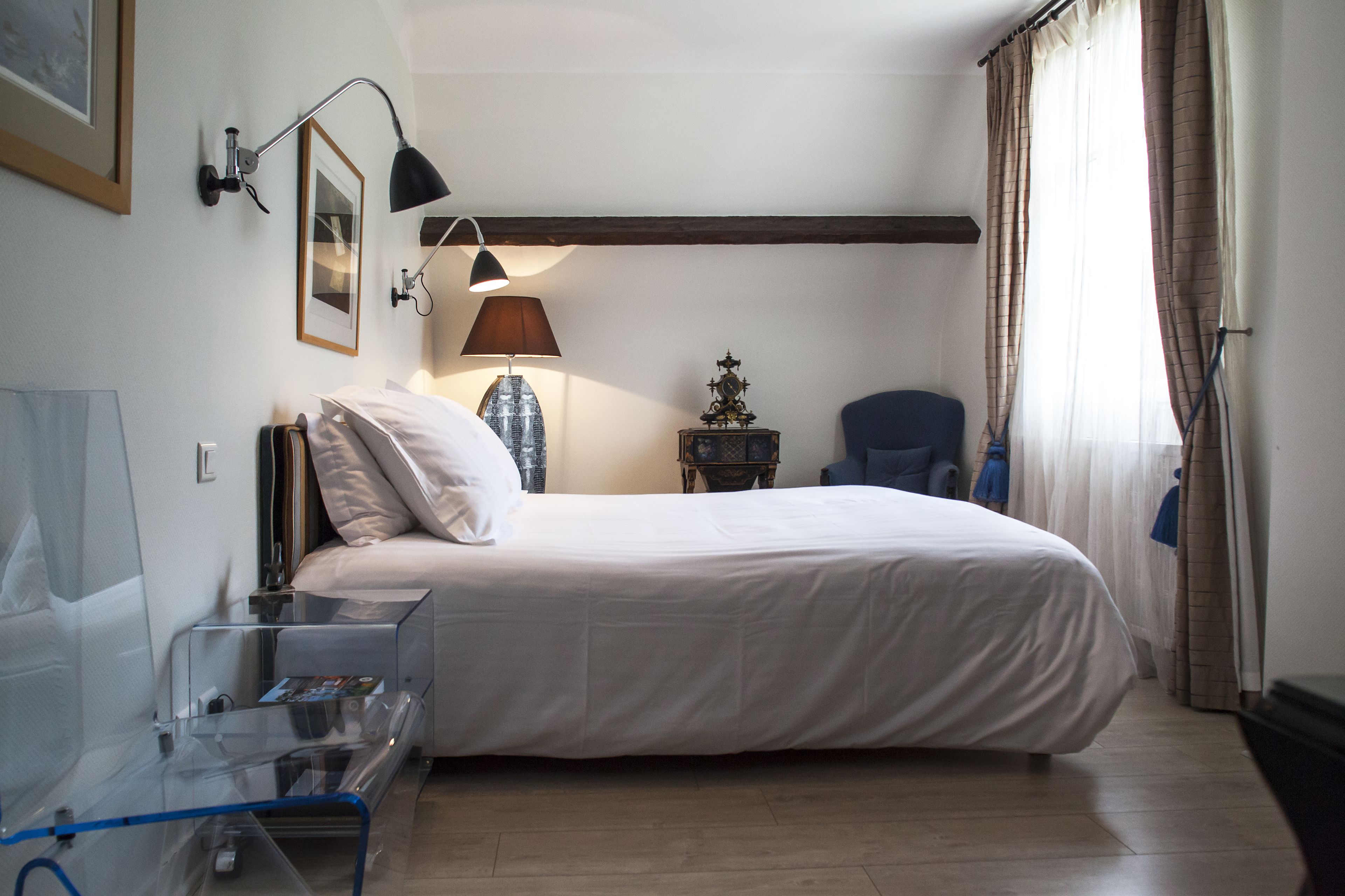 Ein Hotelzimmer mit einem großen Bett, einem Schreibtisch mit Lampe, einem Sessel und einem kleinen Tisch mit Dekoration.