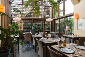 Ein Restaurant mit Innenbereich, großen Fenstern und Blumentöpfen.