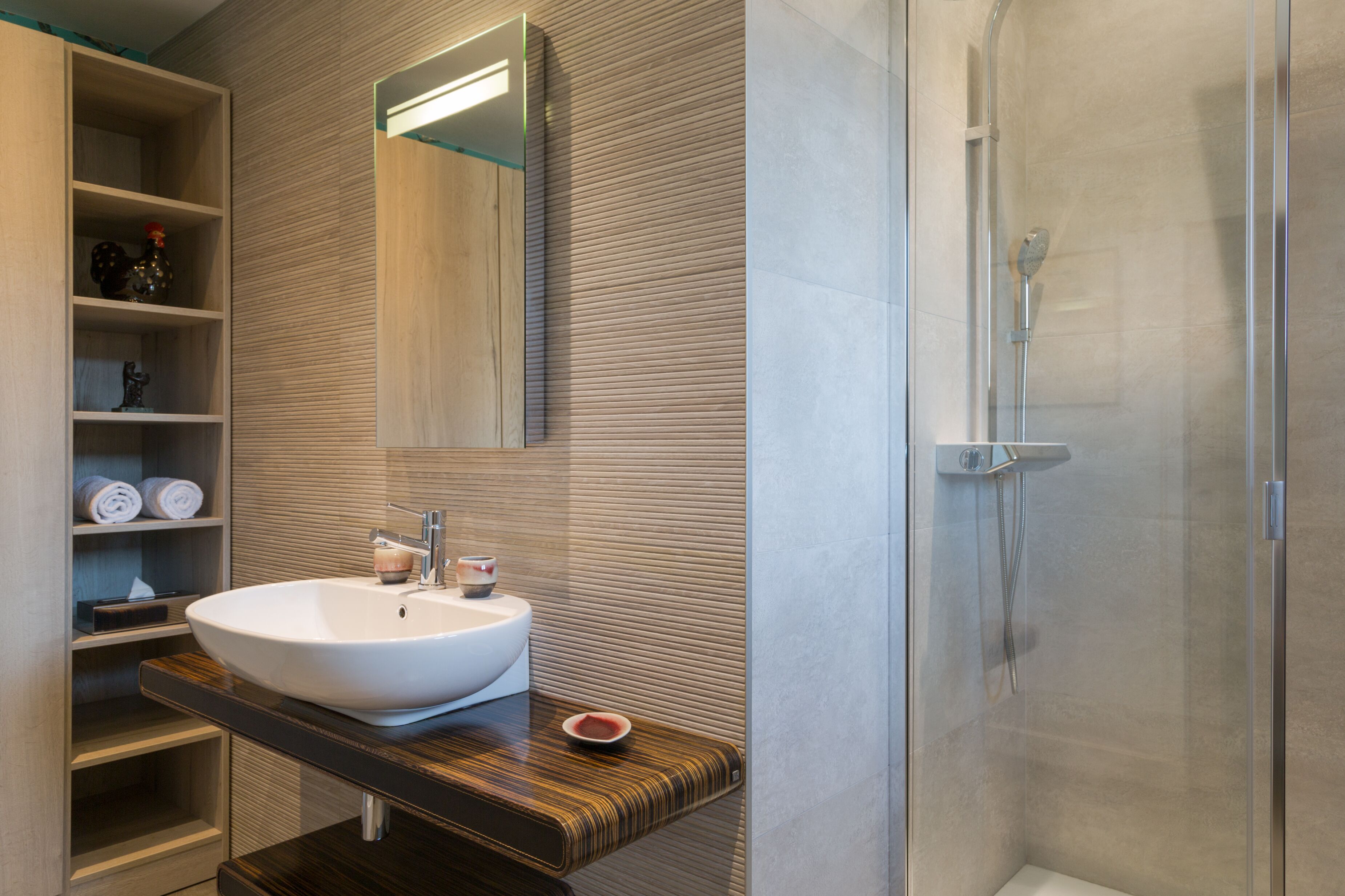 A modern bathroom with a large white sink, a mirror, and a glass-enclosed shower.
