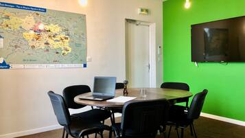 A conference room with a map, a laptop, and a green wall.