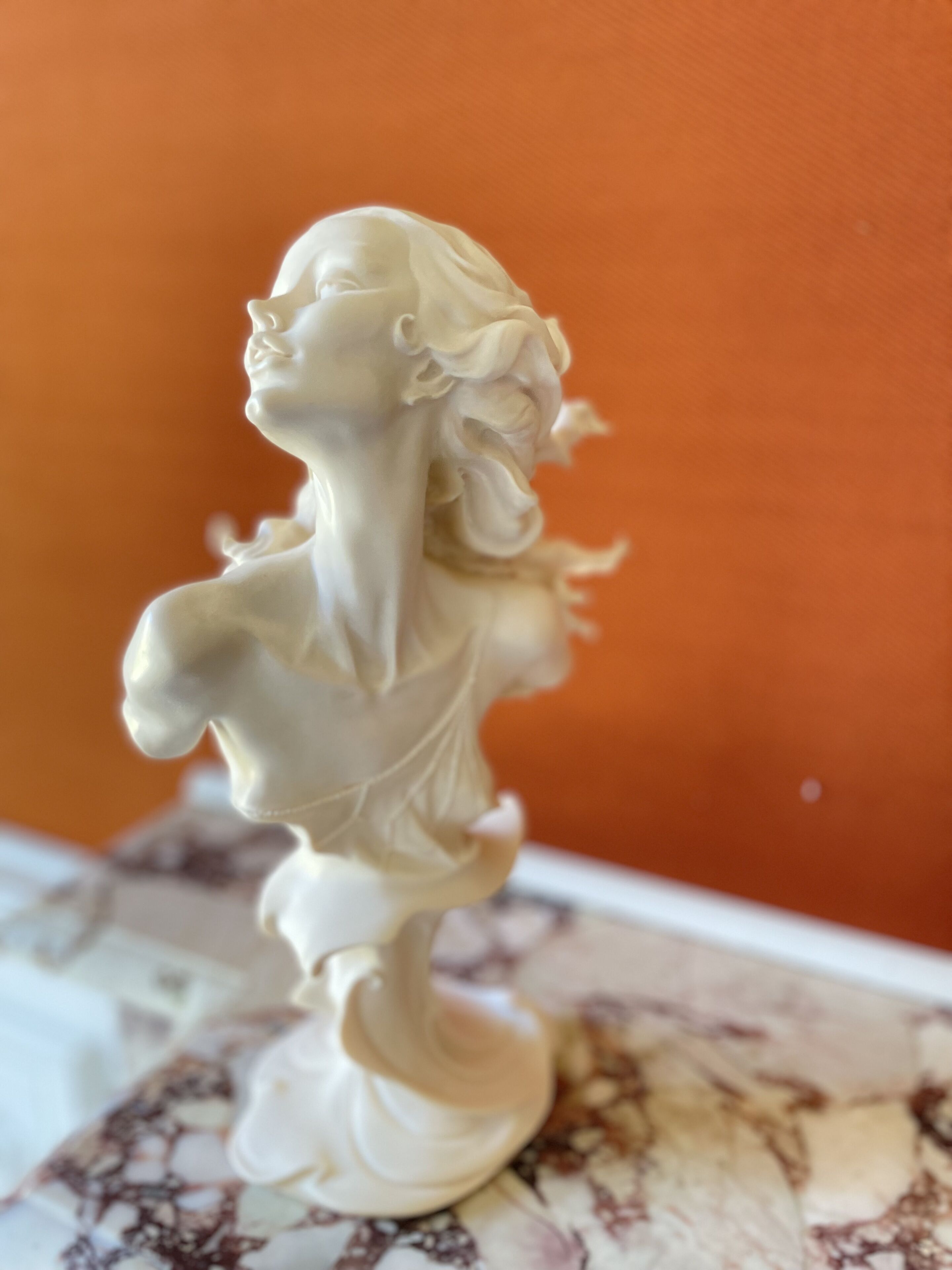 Une sculpture en buste sur un socle de marbre.