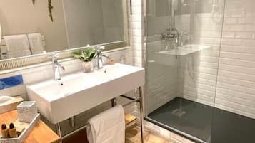 A modern bathroom with a white sink, mirror, and glass shower enclosure.