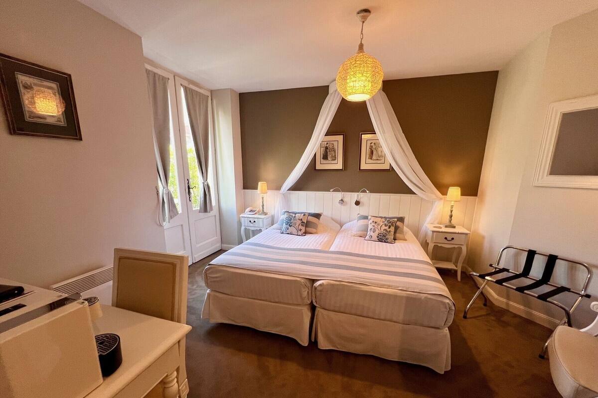 A hotel room with a large bed, a desk, a chair, and a canopy bed.