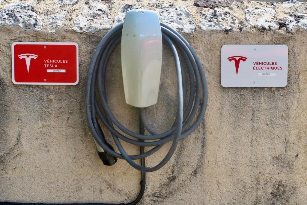 Una estación de carga de Tesla con dos carteles que indican que es para vehículos Tesla y eléctricos.