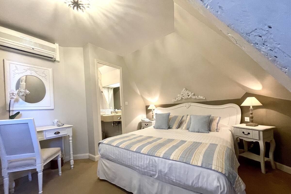 A bedroom with a bed, bedside tables, a desk, and a chair.