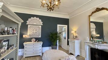 A bedroom with a bed, dresser, mirror, chandelier, and decorative wall panels.