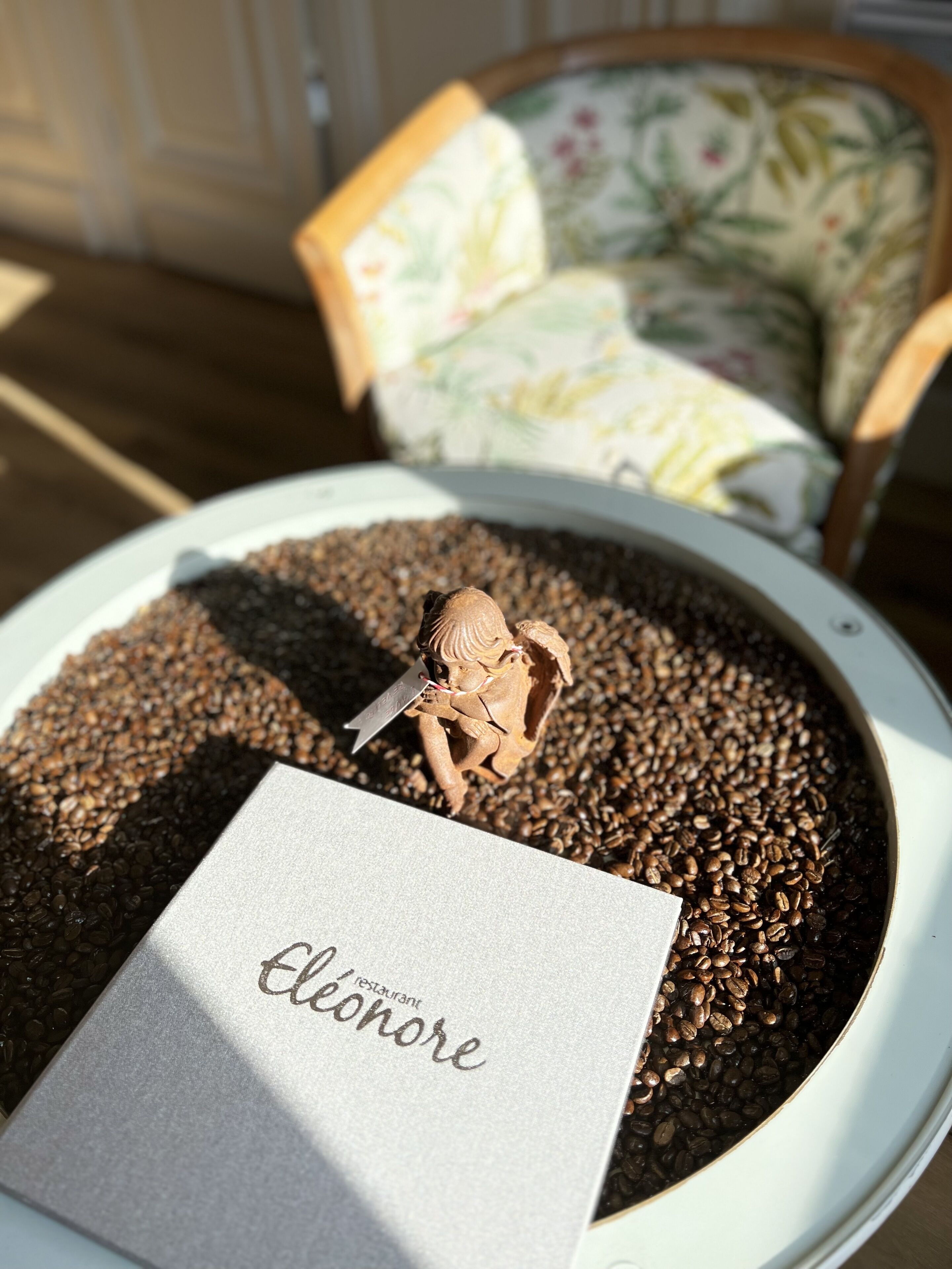 Een bord met koffiebonen, een klein beeldje en een kaartje met de tekst 'Eclonore restaurant'.