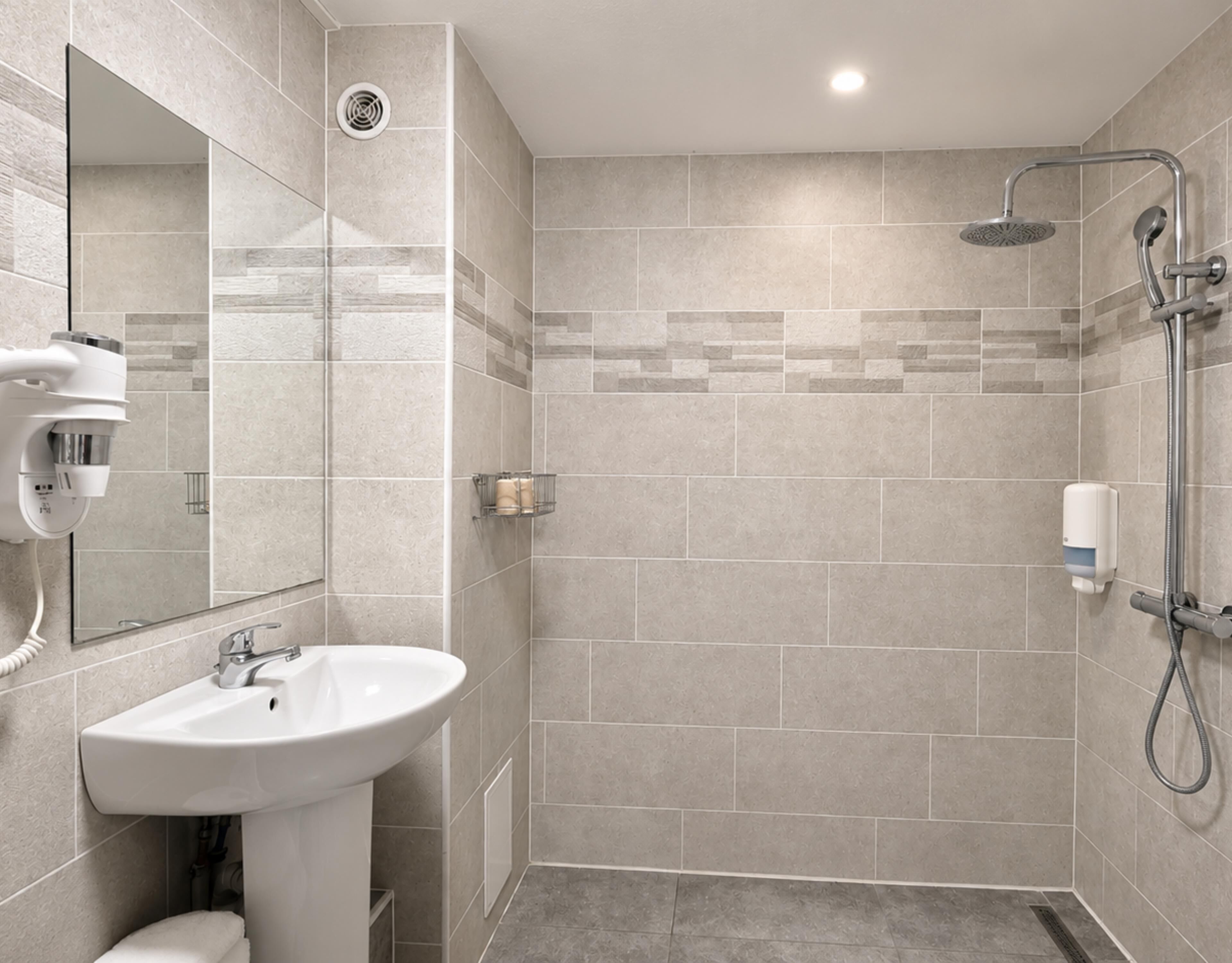 Un baño moderno con lavamanos, espejo y ducha.