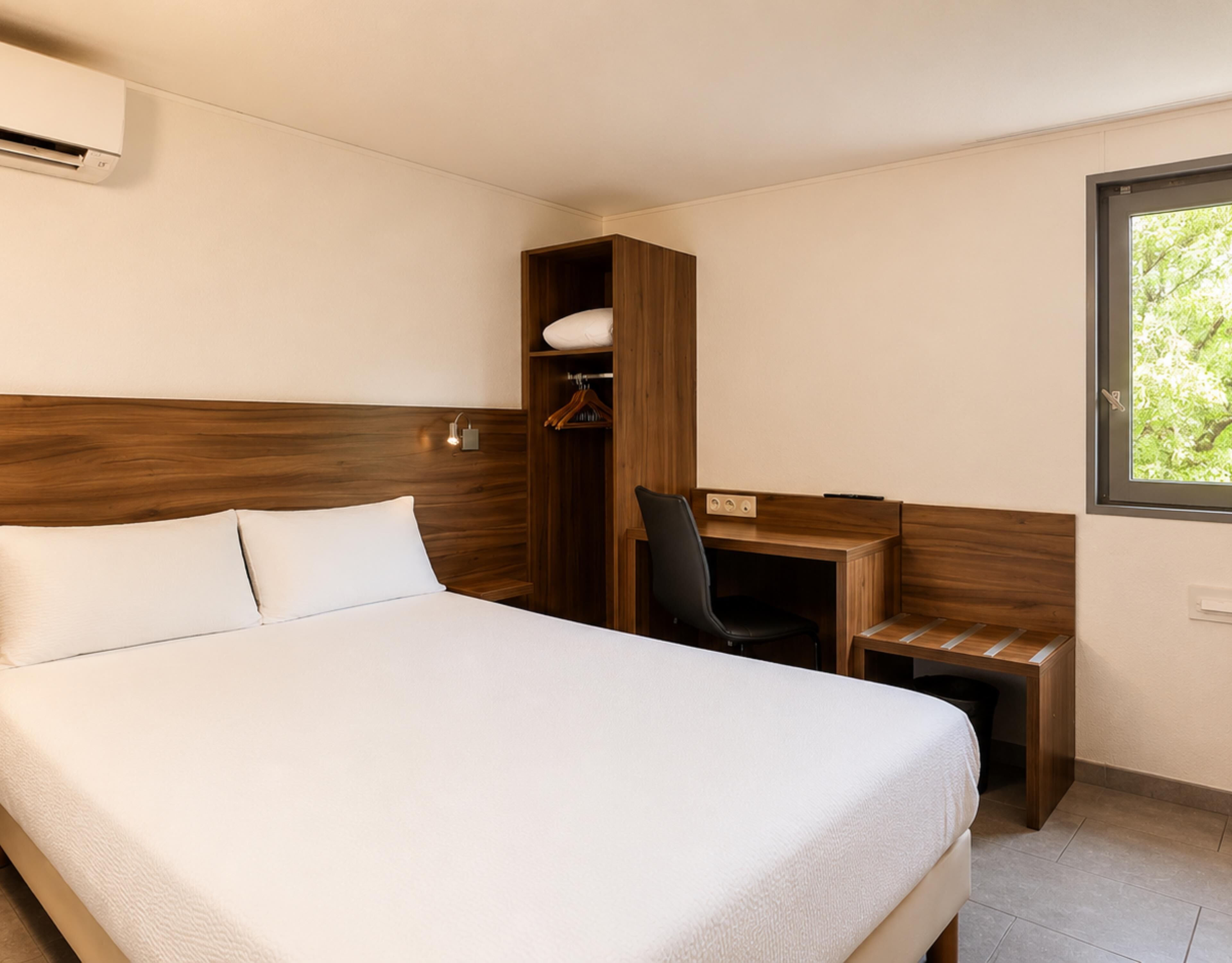 Une chambre d’hôtel avec un lit, un bureau et une armoire.
