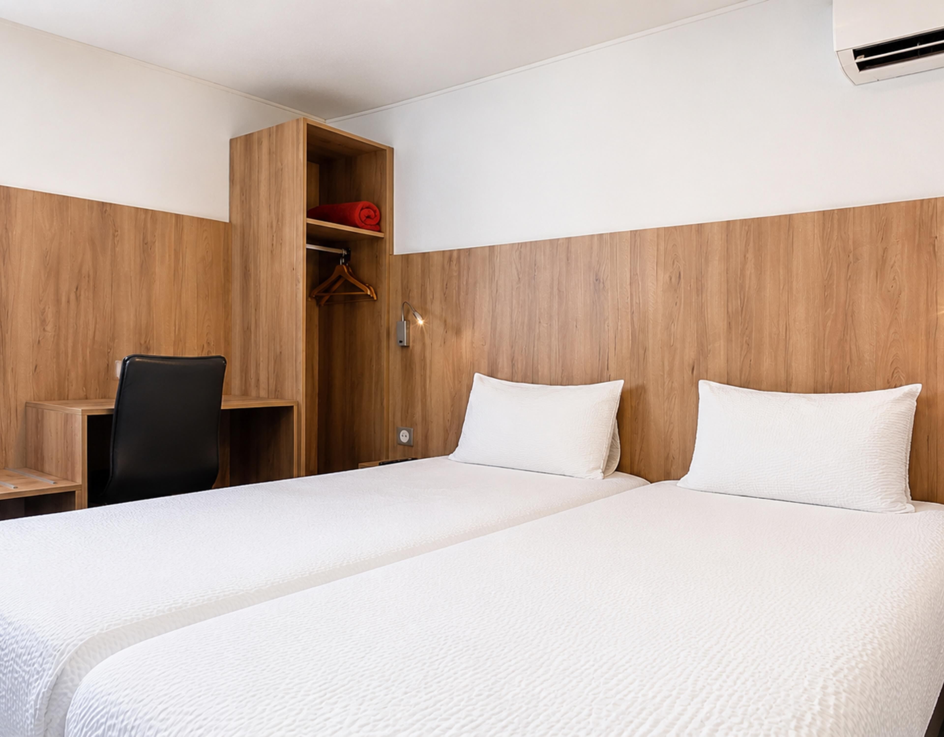 Une chambre d’hôtel avec deux lits, un bureau et une armoire.