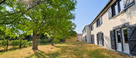 Un barrio residencial con césped, árboles y una fila de casas con persianas.