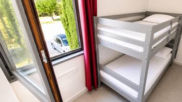 A bunk bed with a window view of a parked car and greenery outside.