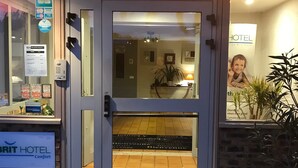 A hotel entrance with a glass door, a reception desk inside, and a sign indicating the hotel name. - Kyriad - Narbonne Sud (Narbonne)