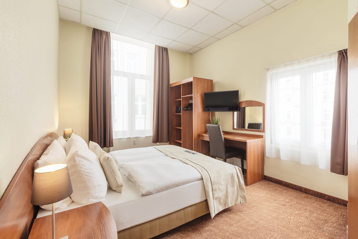 Une chambre d’hôtel comprenant un lit, un bureau, une chaise, une télévision et une armoire.