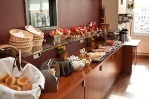 A buffet setup with various food items, baskets, and a toaster. - Hotel Hamburg (Hamburg)