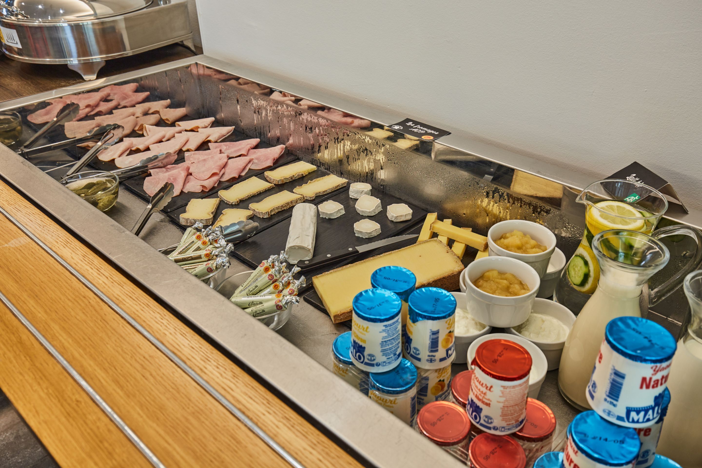 A buffet with various meats, cheeses, and condiments.