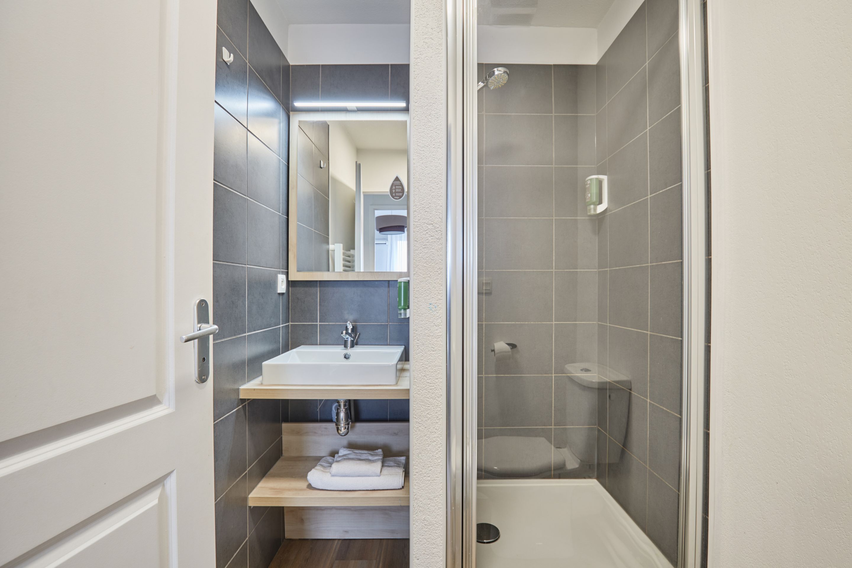 Un bagno moderno con lavandino bianco, specchio e zona doccia.