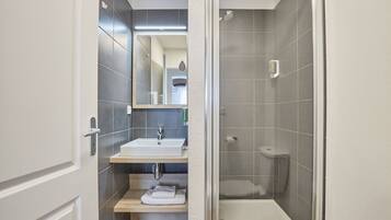 Un bagno moderno con lavandino bianco, specchio e zona doccia.