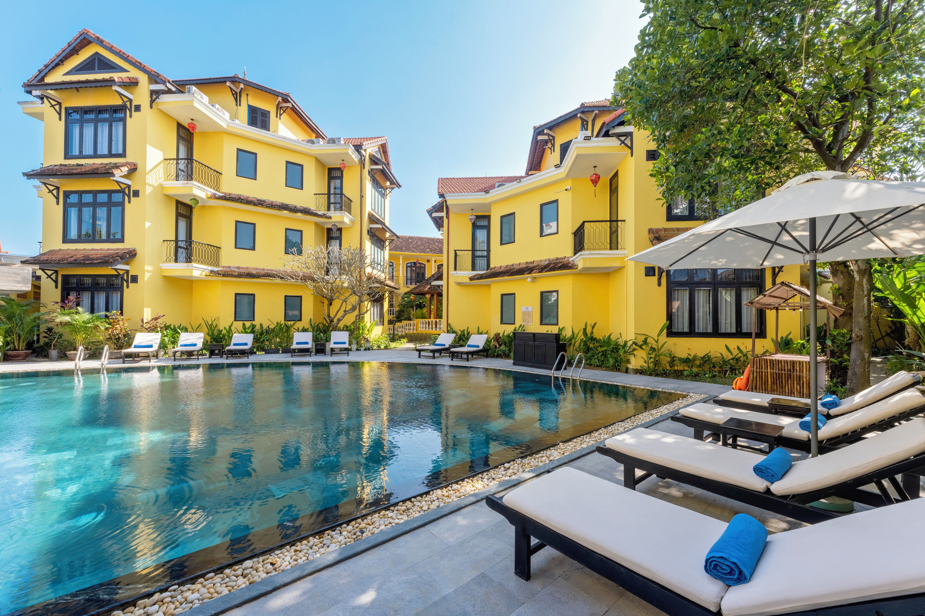 A pool area with lounge chairs and a building with balconies.