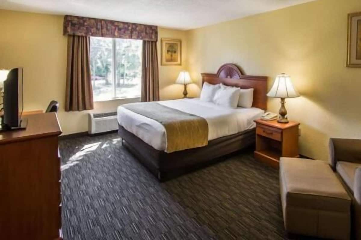 A hotel room with a bed, bedside lamps, a desk, and a chair.