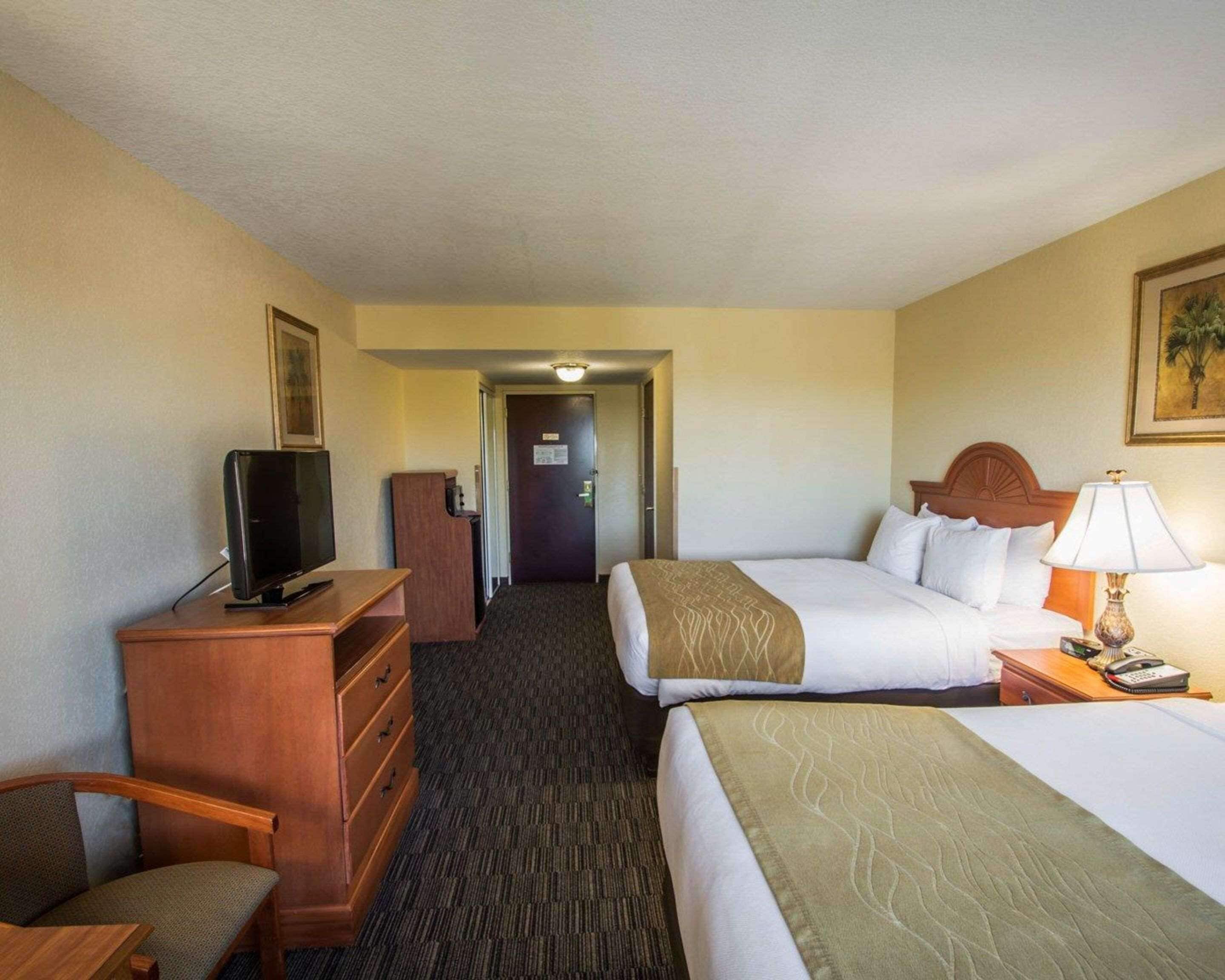 Een hotelkamer met een bed, een bureau met een televisie, een dressoir en een lamp.
