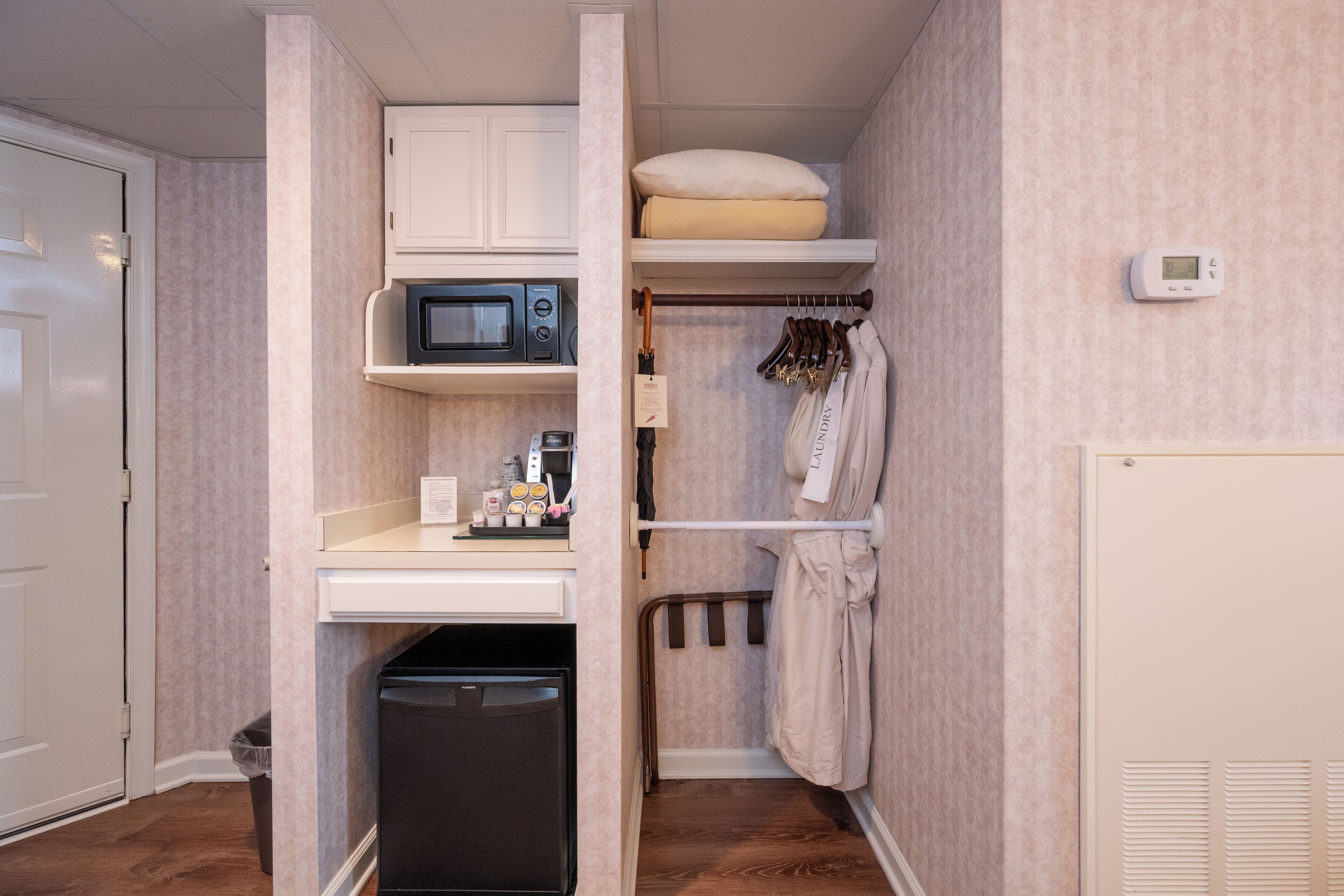 Una kitchenette compacta equipada con microondas, un refrigerador pequeño y un lavamanos.