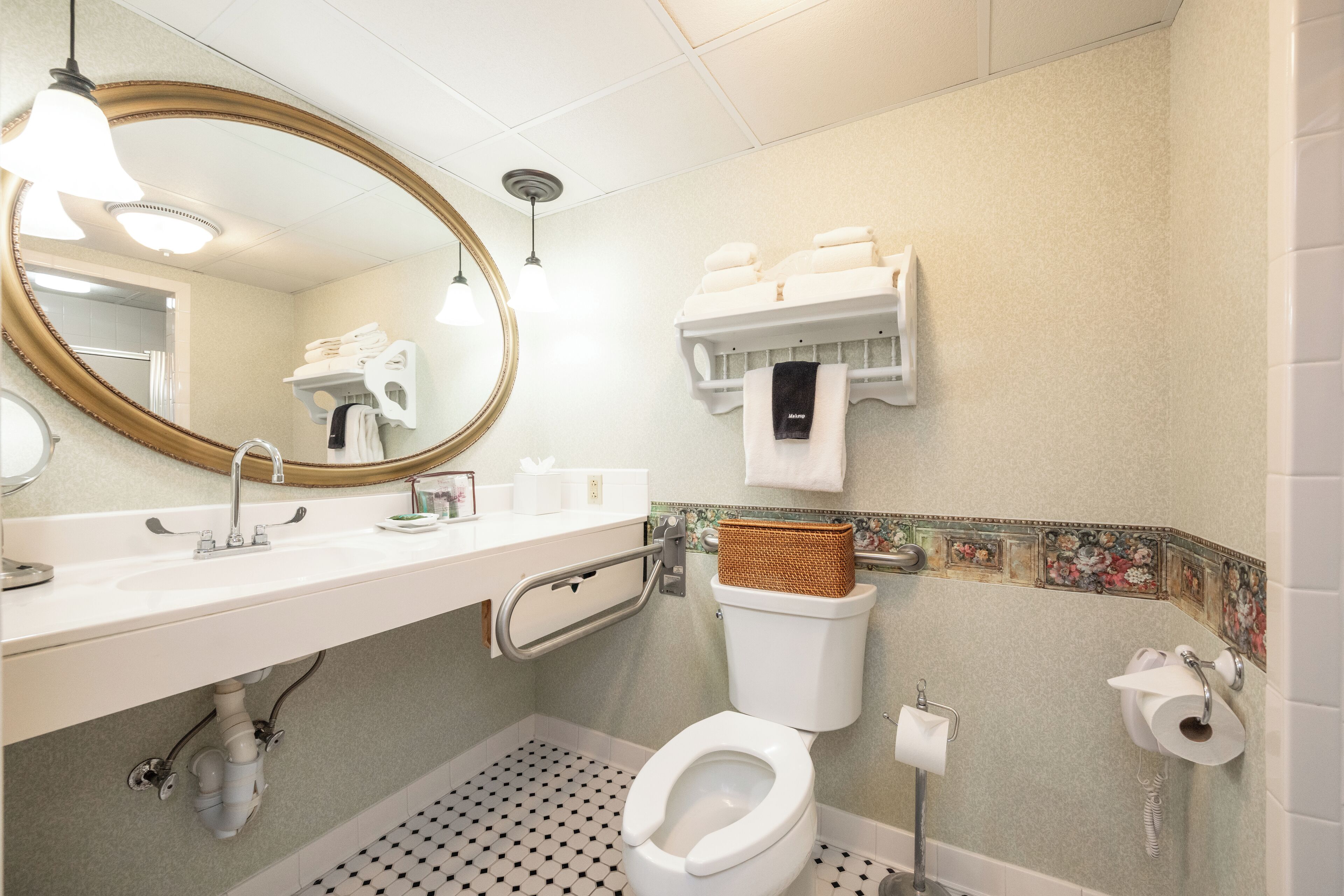 A bathroom with a white sink, a large mirror, a toilet, and a towel rack.