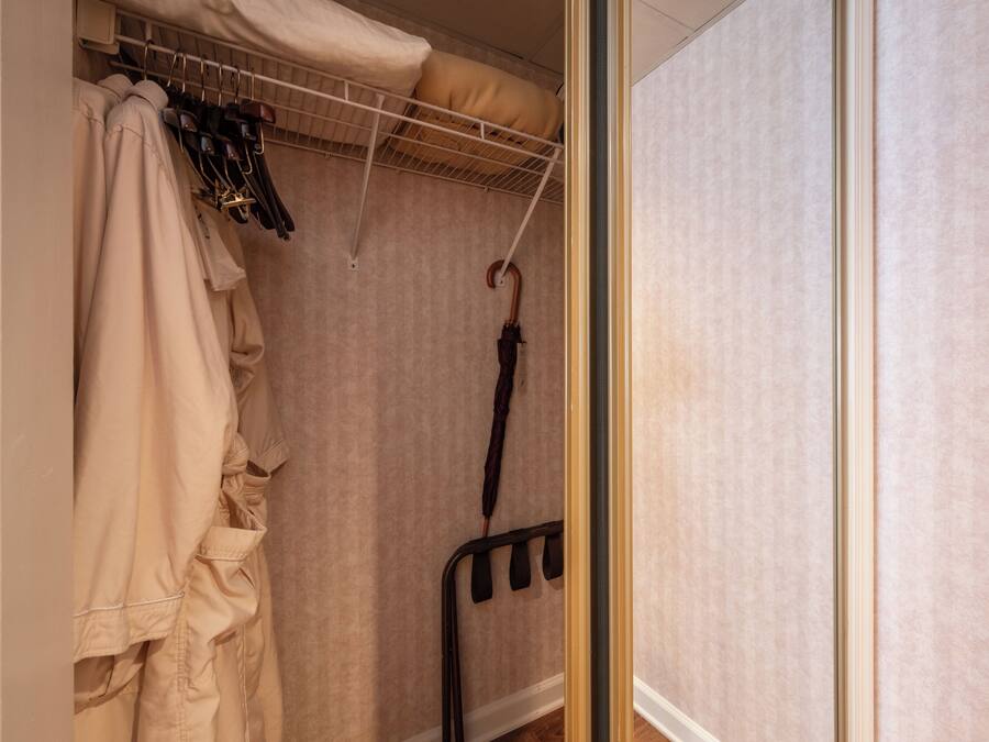 A walk-in closet with hanging clothes and an umbrella.