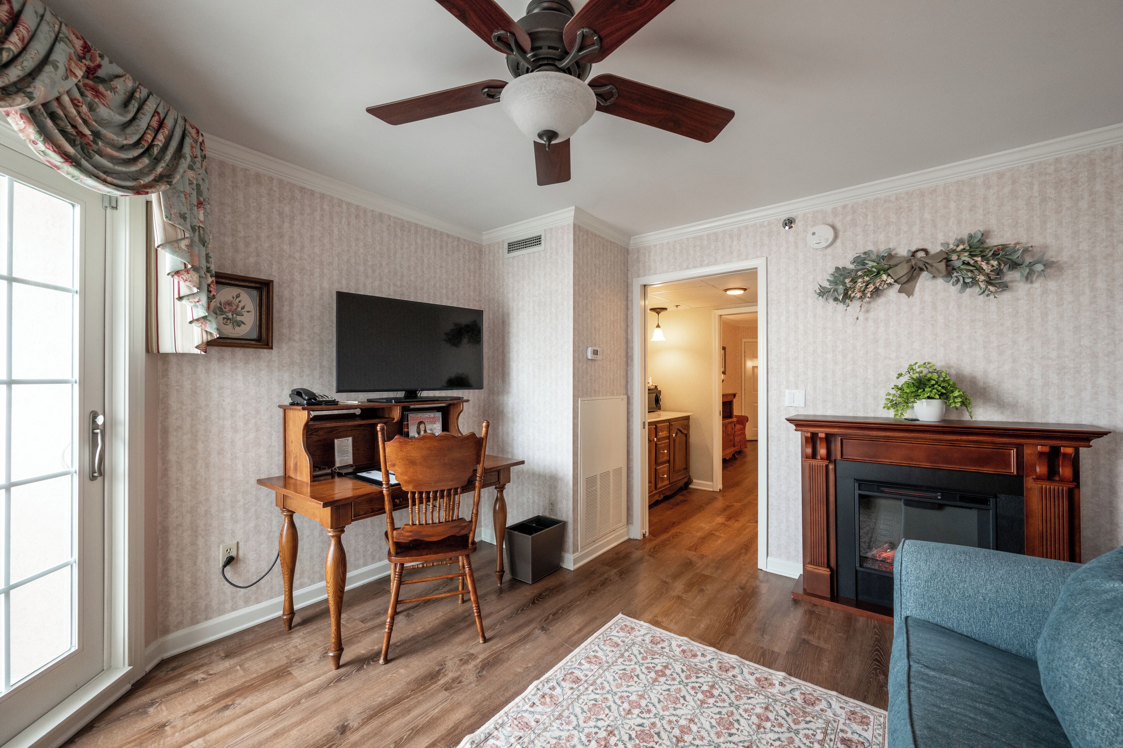 Una sala de estar con chimenea, televisor, ventilador de techo y comedor con mesa y sillas.