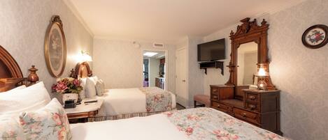 A bedroom with two beds, a dresser, a mirror, and a television.
