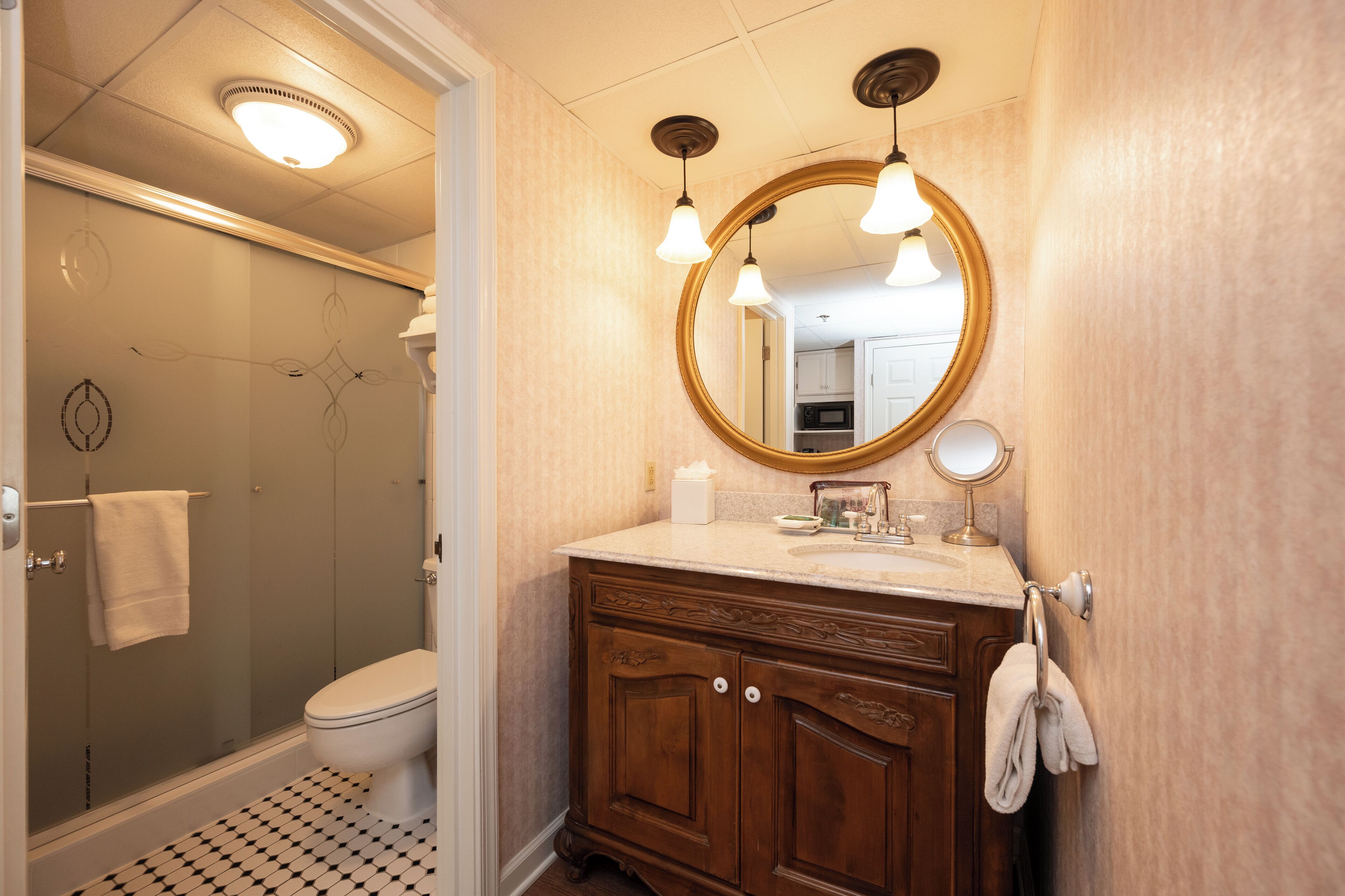 A bathroom with a shower, toilet, vanity with a mirror, and a towel rack.