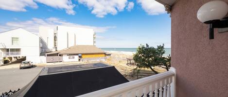Un balcon avec vue sur la plage, les bâtiments et un ciel dégagé.