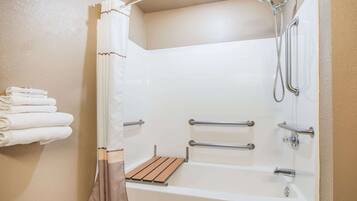 Un baño moderno con bañera, ducha y barras de apoyo.