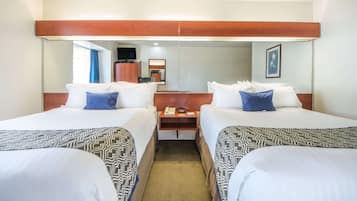 Quarto de hotel com duas camas, uma cabeceira de madeira, mesa de cabeceira com telefone e um espelho.