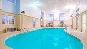 An indoor swimming pool with a clear blue water, surrounded by beige walls and windows. - Microtel Inn & Suites by Wyndham Miami (Miami)