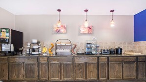 A kitchen with wooden cabinets, a coffee station, and hanging pendant lights. - Microtel Inn & Suites by Wyndham Miami (Miami)