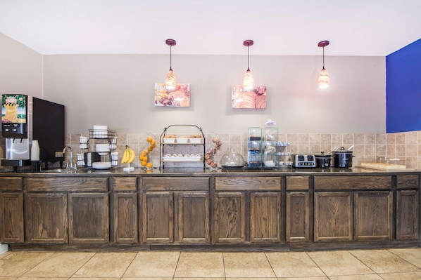 Una cocina con armarios de madera, una estación de café y lámparas colgantes.